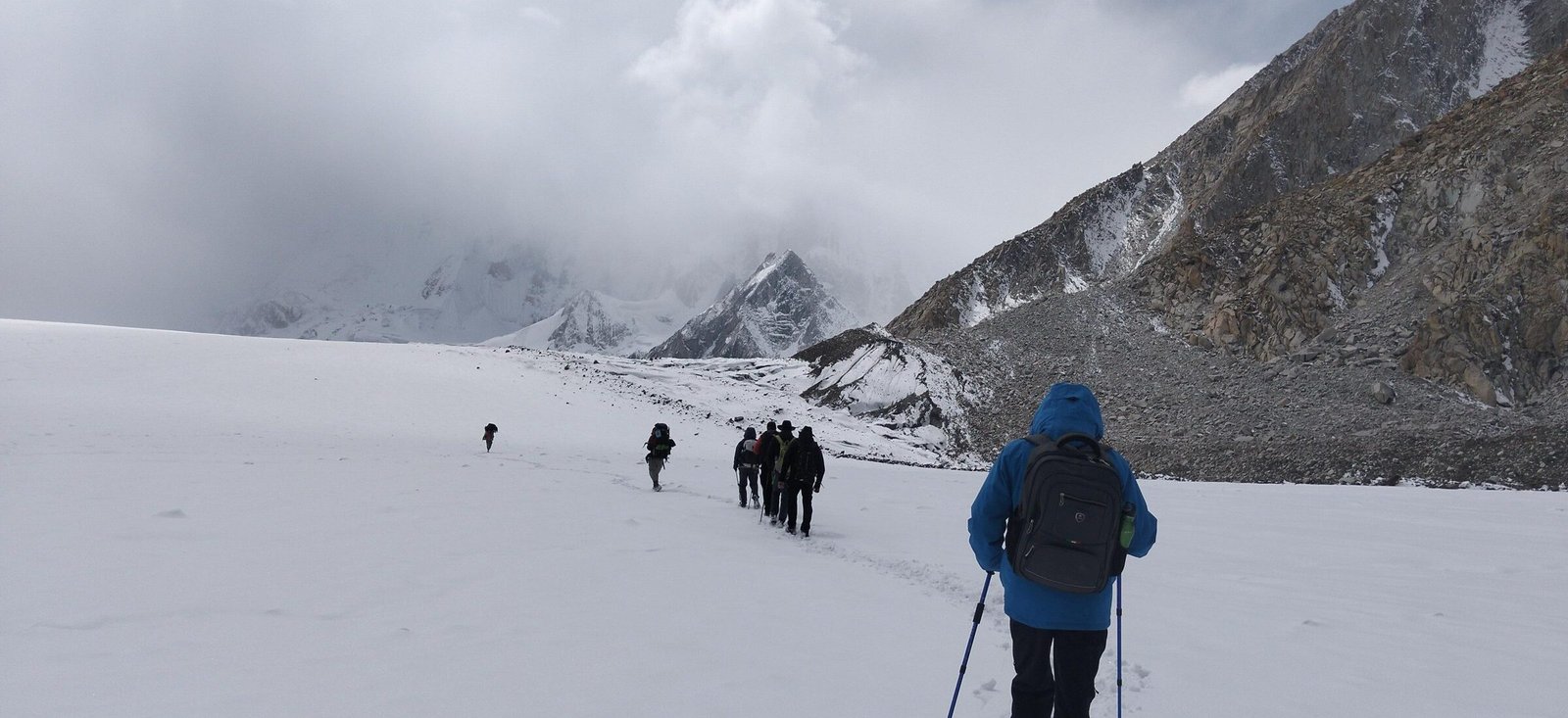 A trekker breaking trail across the snow basin with the party strung out ahead