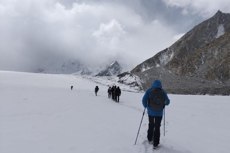 A trekker breaking trail across the snow basin with the party strung out ahead