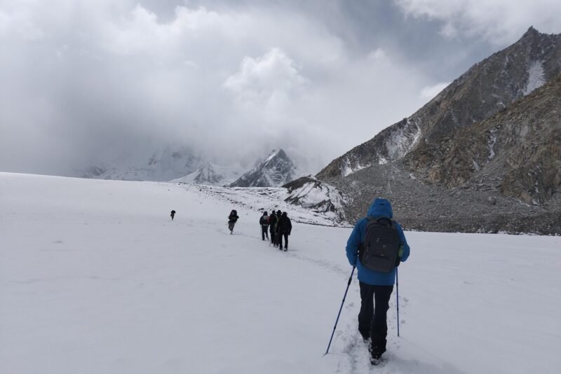 The group crossing open snow toward the headwall, walking poles and a daypack