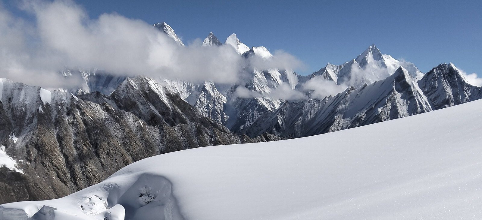 Peaks above the snow ridge with a climber on the crest in the foreground