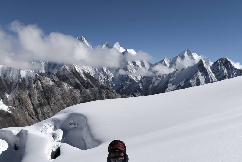 Peaks above the snow ridge with a climber on the crest in the foreground