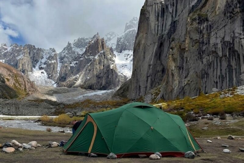 A green tent on the flat ground with the granite towers behind